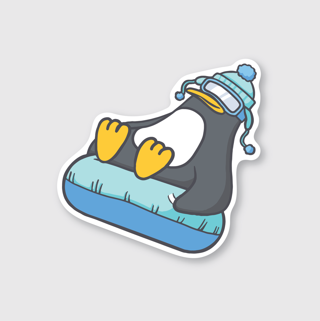 The Penguin Tubing Sticker features a delightful cartoon penguin wearing ski goggles and a blue hat, sliding down on a blue and white snow tube. Its yellow feet pop against the light gray background, showcasing the charm of Seattle artistry.