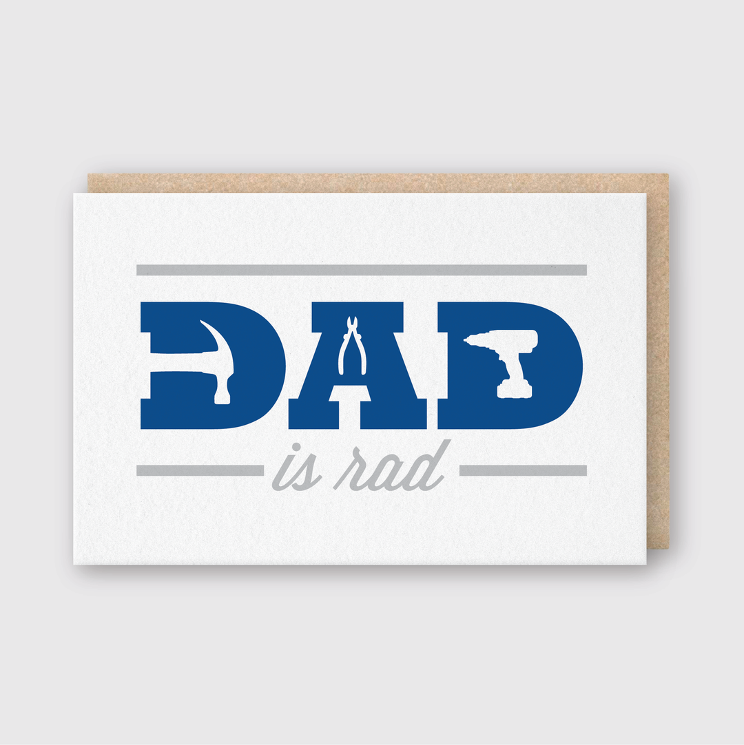 The "Dad Is Rad" greeting card is a handcrafted item showcasing a minimalist design with the phrase integrated alongside illustrations of a hammer, pliers, and power drill. Perfect for Father's Day, this card features blue and gray text on a clean white background and is paired with a brown envelope.