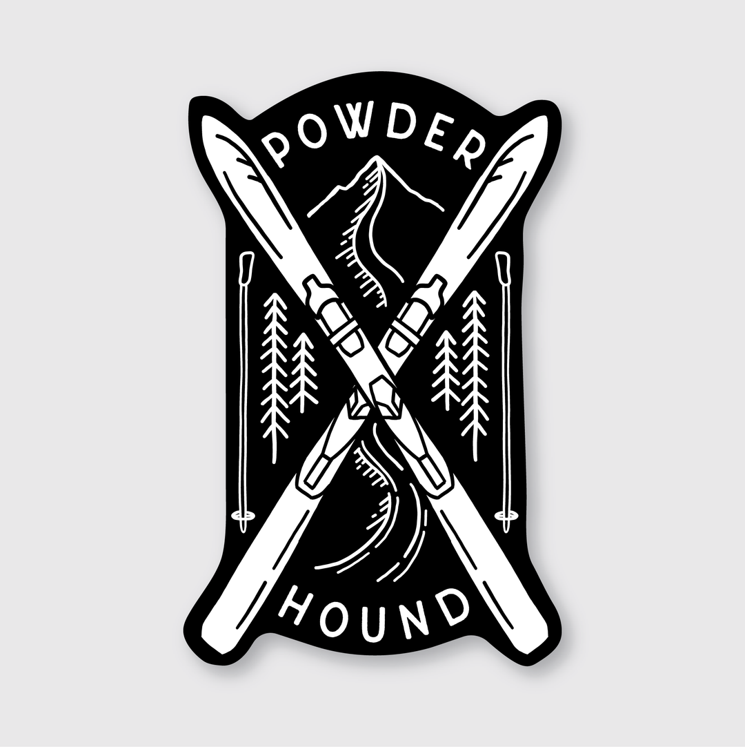 The Powder Hound Sticker showcases a black and white design featuring crossed skis and poles, set against a scenic backdrop of pine trees and mountains. Above and below the skis, the phrase "Powder Hound" is stylishly displayed, embodying Seattle's essence through skilled artistry.