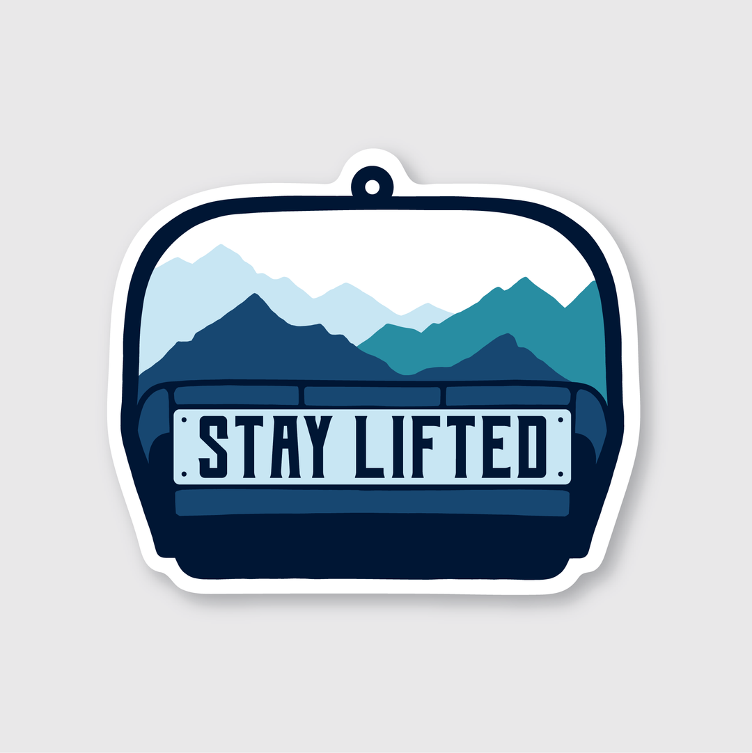 The Stay Lifted Sticker is a stylized vinyl sticker designed to withstand various weather conditions. It features a graphic of a car dashboard with the words "Stay Lifted," set against a backdrop of blue and teal mountains under a light gray sky, showcasing the creativity of talented artists.