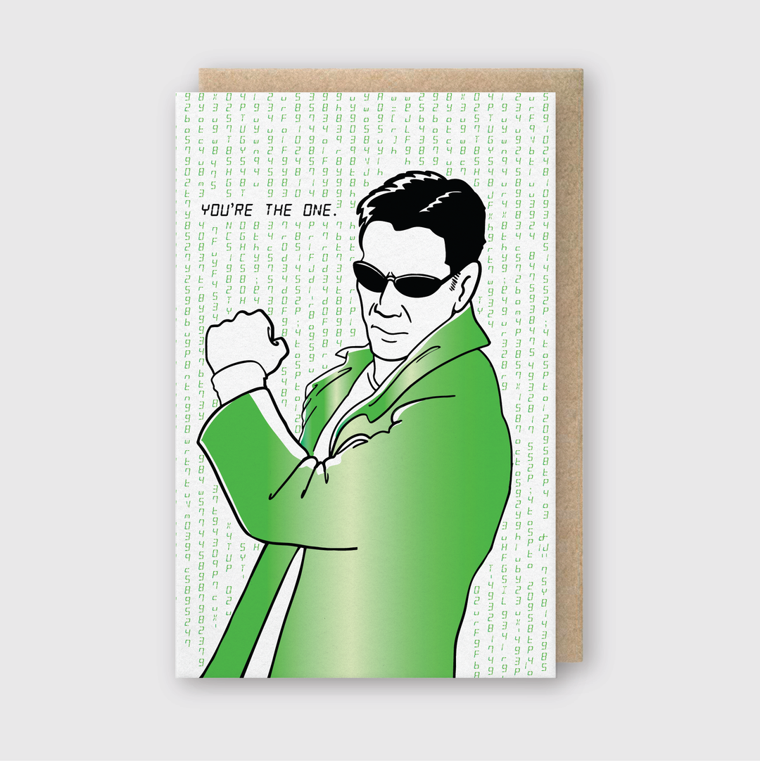This greeting card features an illustration of a person in a green coat and sunglasses, raising a fist against a backdrop of flowing digital code. The text reads, "YOU'RE THE ONE." It's an ideal choice for a romantic gesture, meticulously handcrafted and accompanied by a recycled kraft envelope.