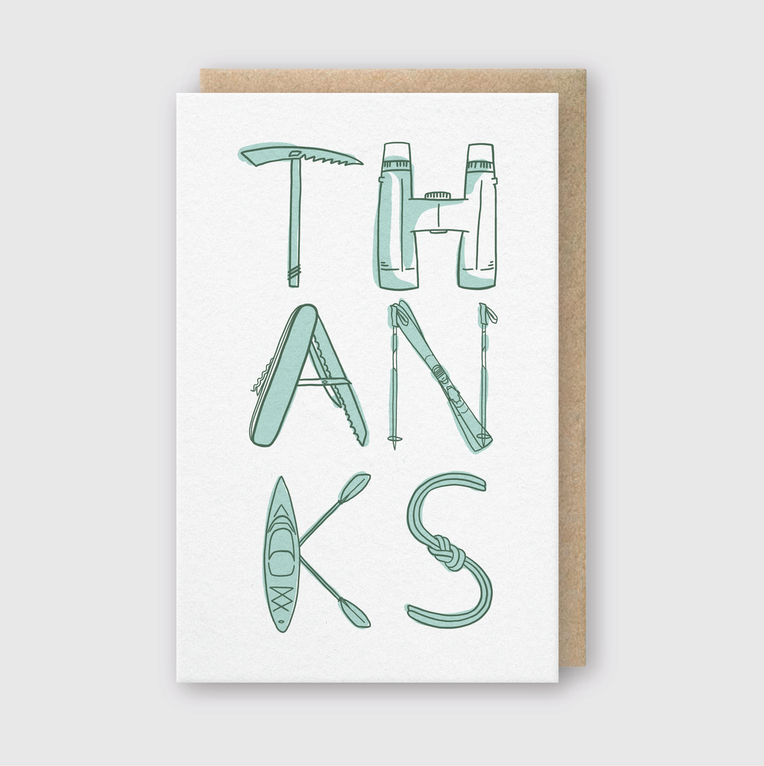The Thanks Gear Handcrafted Thank You Greeting Card features the word "THANKS" creatively designed using illustrations of outdoor adventure gear such as an ice axe, thermos, and kayak. It's printed on FSC-certified paper and includes a brown envelope on a white background, emphasizing its eco-friendly nature.