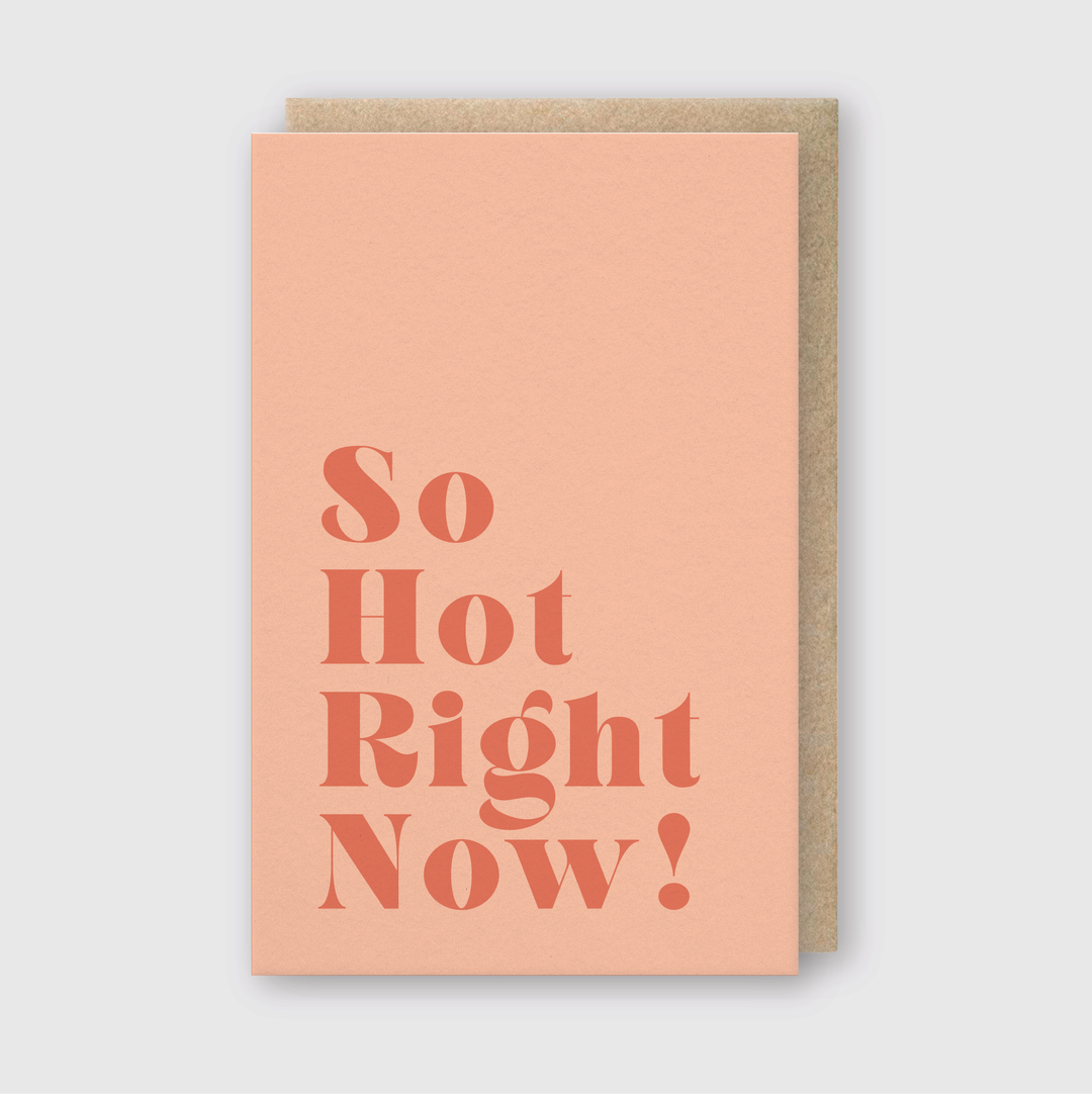 The "So Hot Right Now" Greeting Card is handcrafted, featuring bold dark coral text on a light peach background. Printed with soy-based inks, it rests elegantly against a plain white surface.