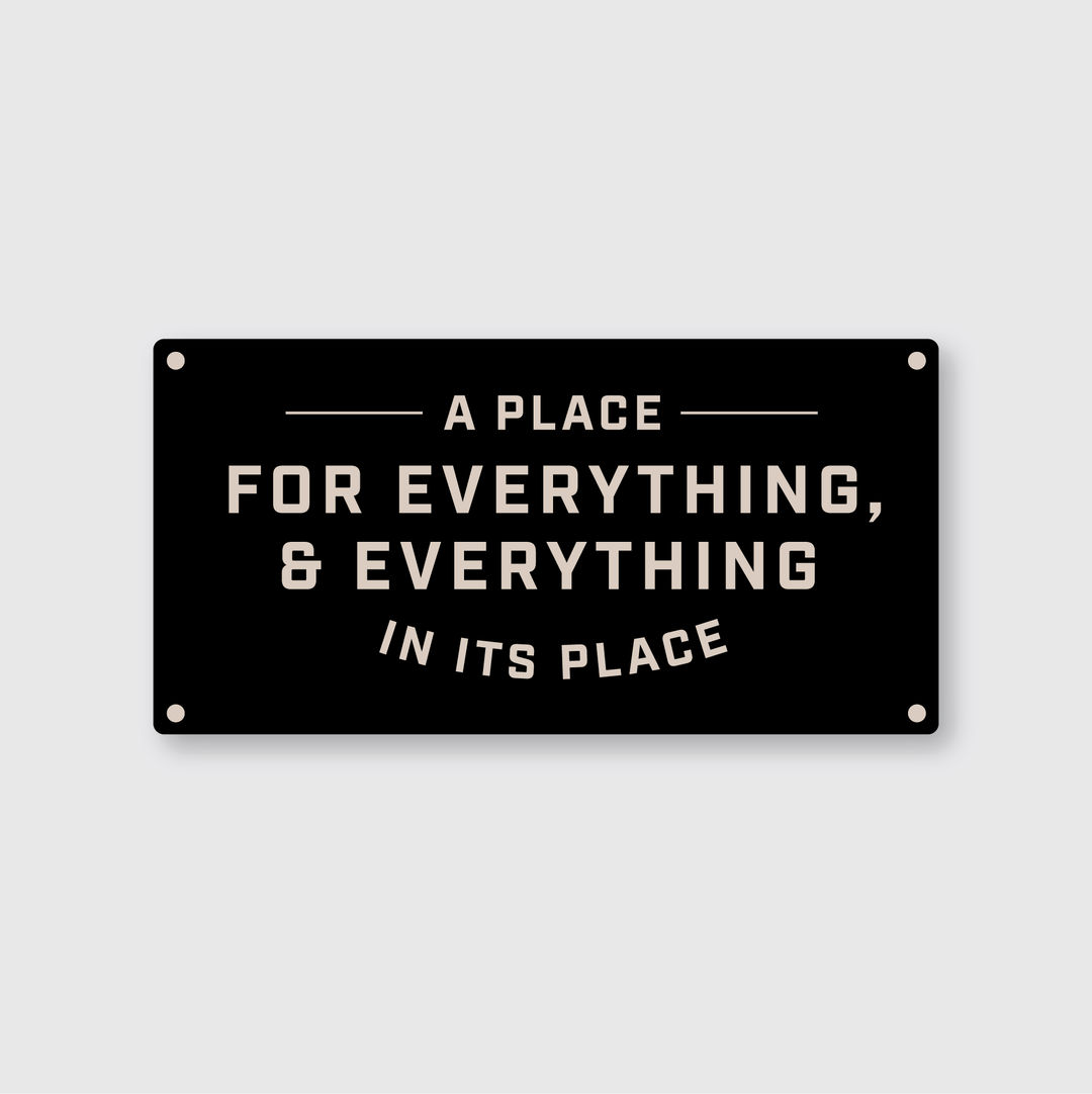 The "Everything In Its Place" sticker by Pike Street Press is a high-quality vinyl piece designed by artists. It showcases bold white text on a black background, stating: "A place for everything, & everything in its place," with decorative lines above and below the text. The sticker is designed for easy mounting, featuring four corner holes.