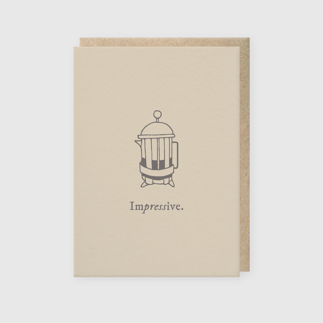 The "Impressive French Press Greeting Card" by Pike Street Press highlights a simple illustration of a French press coffee maker above the word "Impressive." Designed with a beige theme and crafted on a kraft paper base, this card exudes minimalistic and elegant charm.