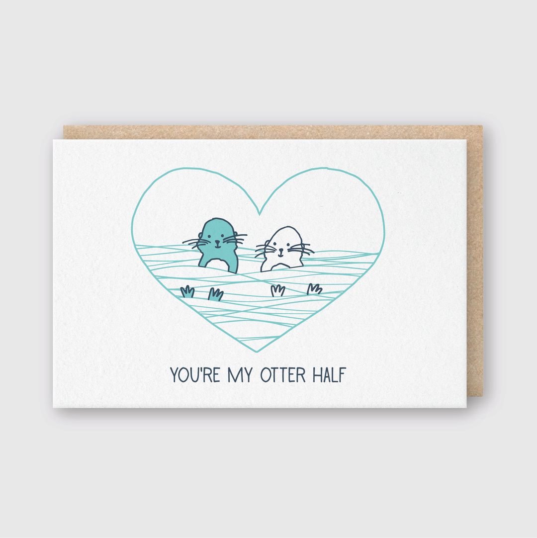 This delightful greeting card features two adorable cartoon otters holding hands within a heart-shaped design. Crafted from FSC certified paper, it includes the sweet message "YOU'RE MY OTTER HALF" and is paired with a brown envelope. The design is set against a minimalist background, making it a charming way to express affection.