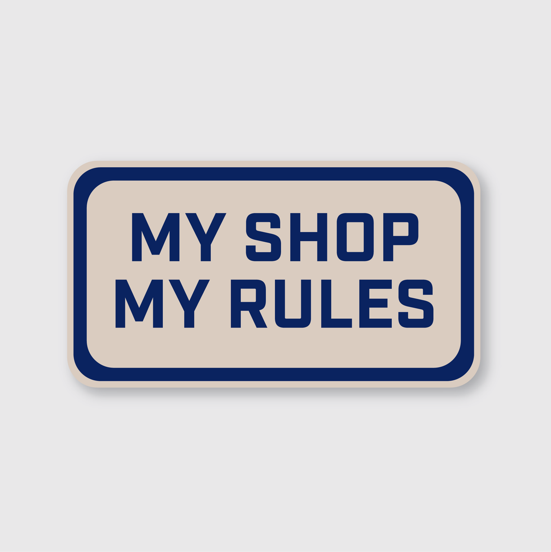 This weather-resistant sticker features a rectangular design with a beige background and a navy blue border. It prominently displays the bold navy blue text: "MY SHOP MY RULES." Designed by independent artists, this stylish and durable piece is offered under the name My Shop My Rules Sticker.