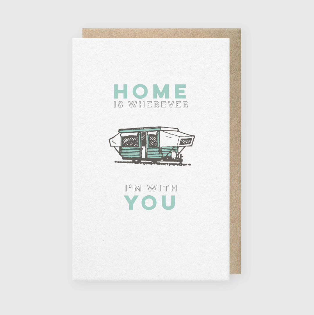 Certainly! The "Home With You Greeting Card" features an illustration of a camper trailer along with the heartfelt message, "Home is wherever I'm with you." It includes a recycled kraft envelope, adding an eco-friendly touch to its thoughtful design.