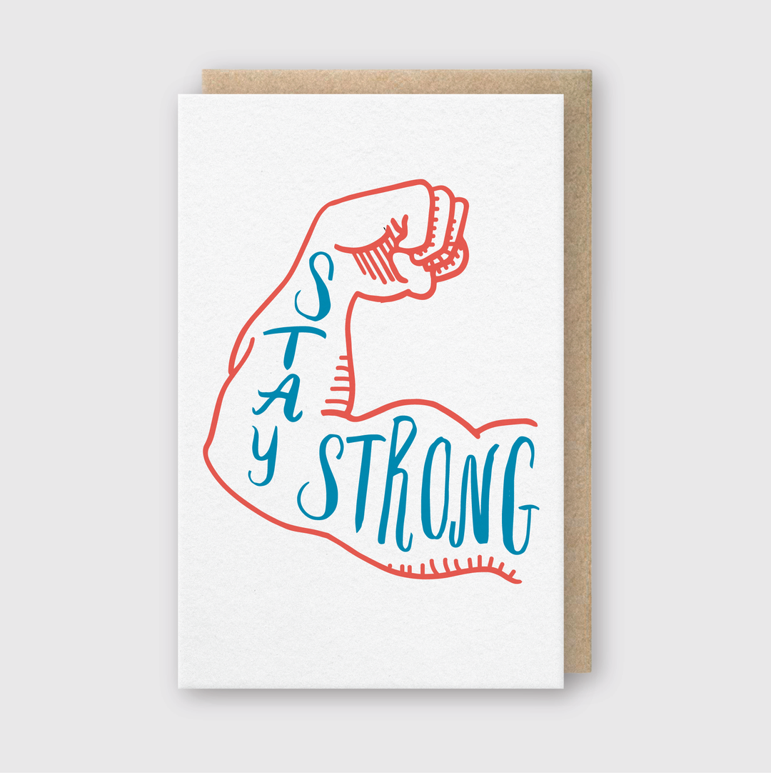 The Stay Strong Greeting Card features a handcrafted design with an illustration of a muscular arm flexing, complemented by motivational words outlined in blue and red. It has a light gray background and comes with an elegantly paired brown envelope, making it perfect for sending encouragement.