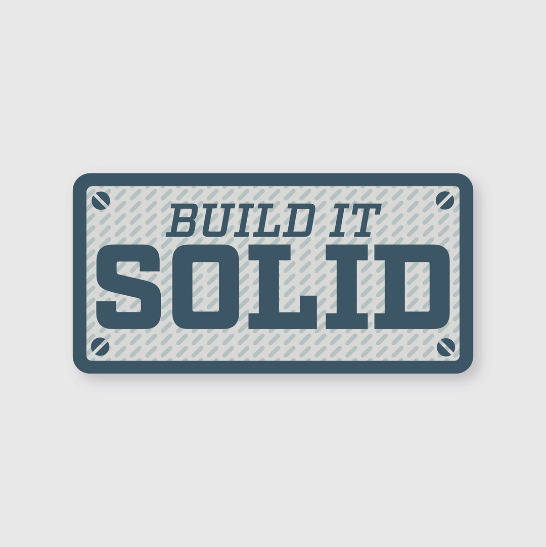 Introducing the "Build It Solid Sticker": This premium rectangular piece features a textured background and resembles a die-cut vinyl sticker. It displays the phrase "BUILD IT SOLID" in bold blue letters, creatively designed with four screw head designs in each corner for an industrial look.