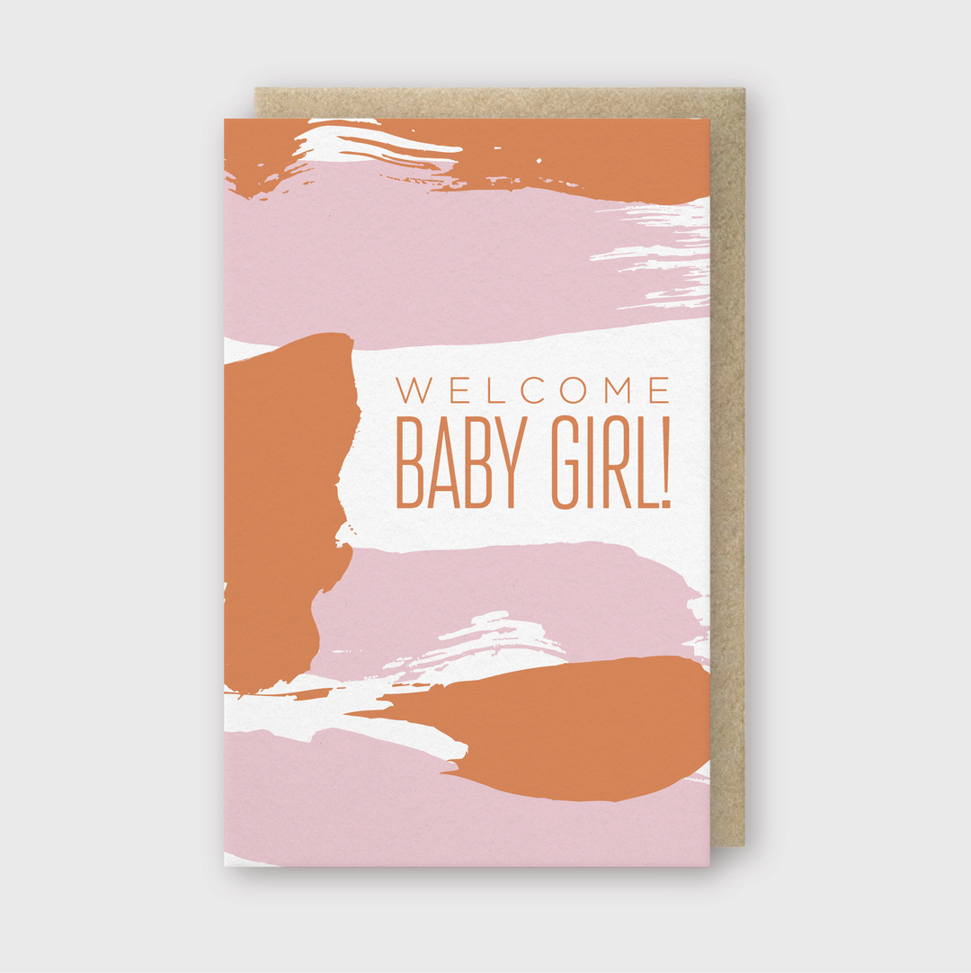 The Welcome Baby Girl Greeting Card features abstract orange and pink brush strokes on the front, with the message "Welcome Baby Girl!" beautifully printed in orange. The design is set against a light gray background, perfectly capturing the joy of a new arrival.