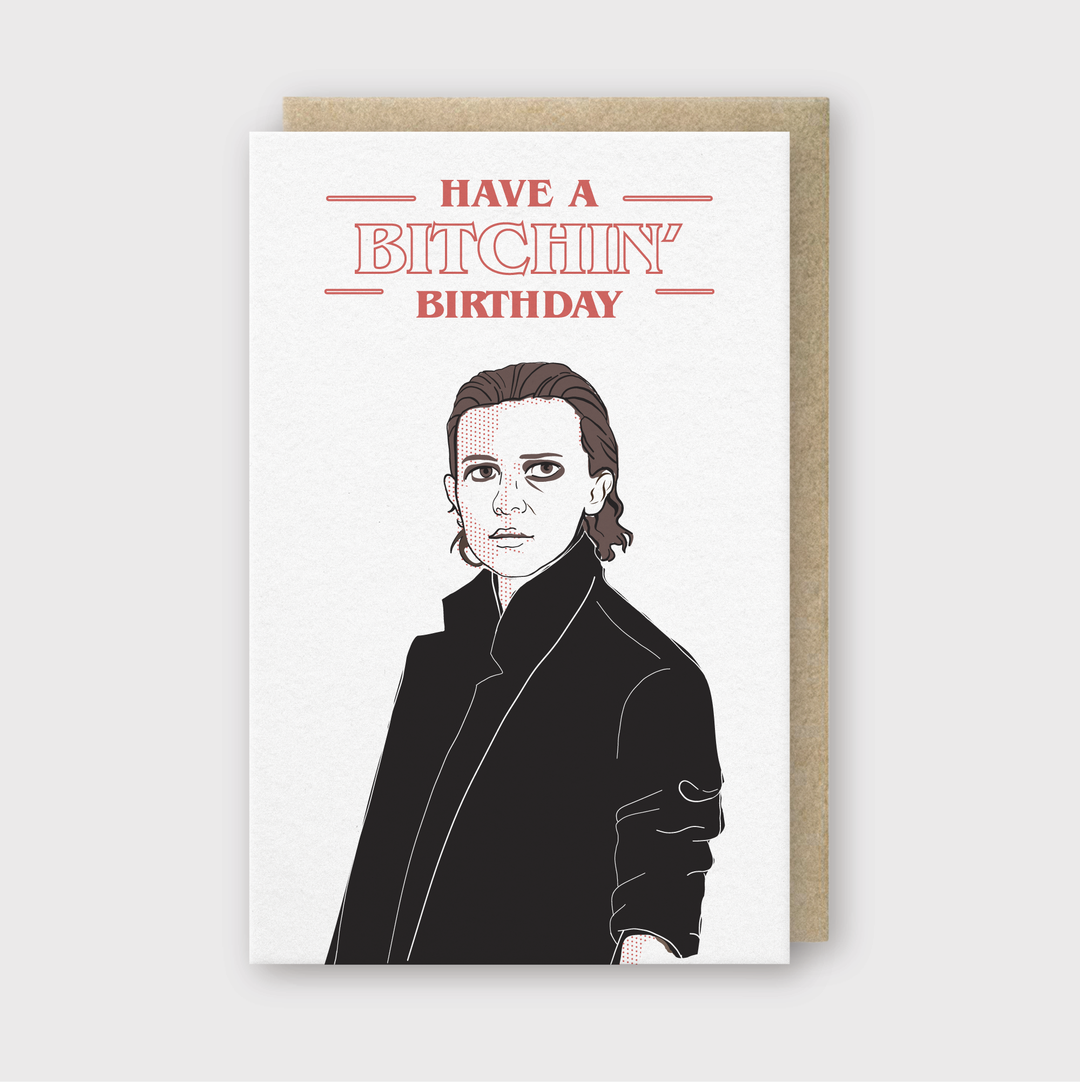 The Bitchin' Birthday Greeting Card features a black and white illustration of a person in a coat, highlighted by bold red text saying "Have a Bitchin' Birthday." This card is letterpress printed on FSC Certified Paper and comes with a brown envelope, all set against a light gray backdrop.