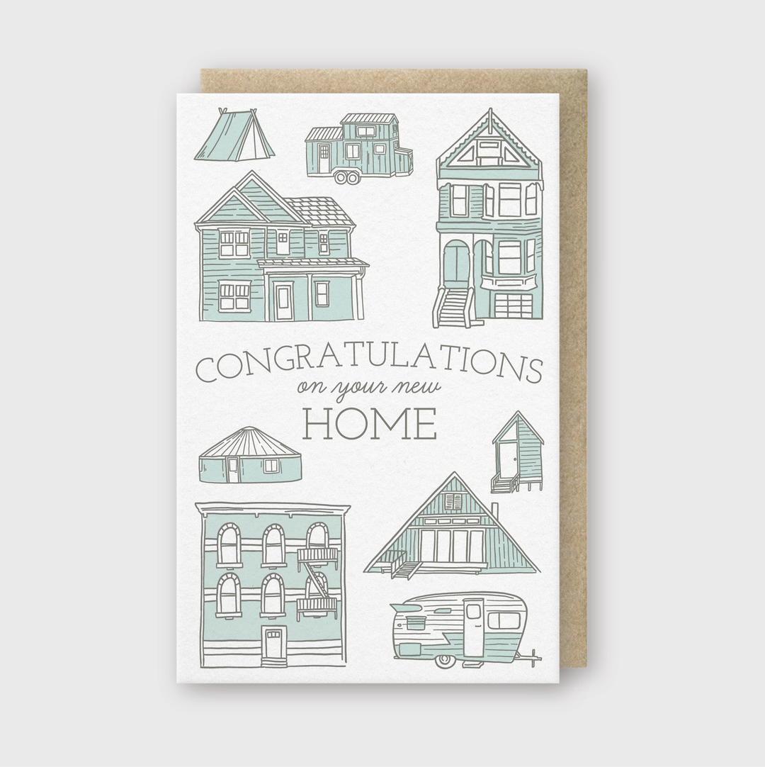 The greeting card you're referring to showcases an illustrated letterpress design featuring various home designs such as houses, a tent, a camper, and a treehouse. It contains the message "Congratulations on your new home" and is paired with a brown envelope for an elegant touch.