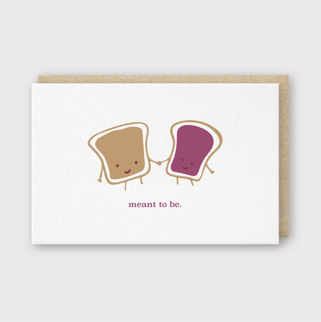 This charming greeting card showcases a delightful illustration of two joyful toasts clasping hands, one topped with peanut butter and the other with jelly. Crafted in Seattle with soy-based inks, it is presented on a white background and comes with a brown envelope.