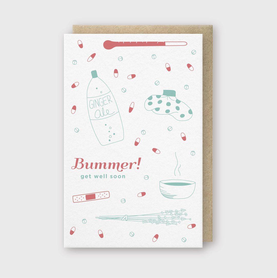 The "Bummer Get Well Soon" greeting card features charming illustrations of ginger ale, a thermometer, a hot water bottle, pills, a steaming soup bowl, and tissues. The vibrant red and teal text conveys sincere hopes for a speedy recovery.