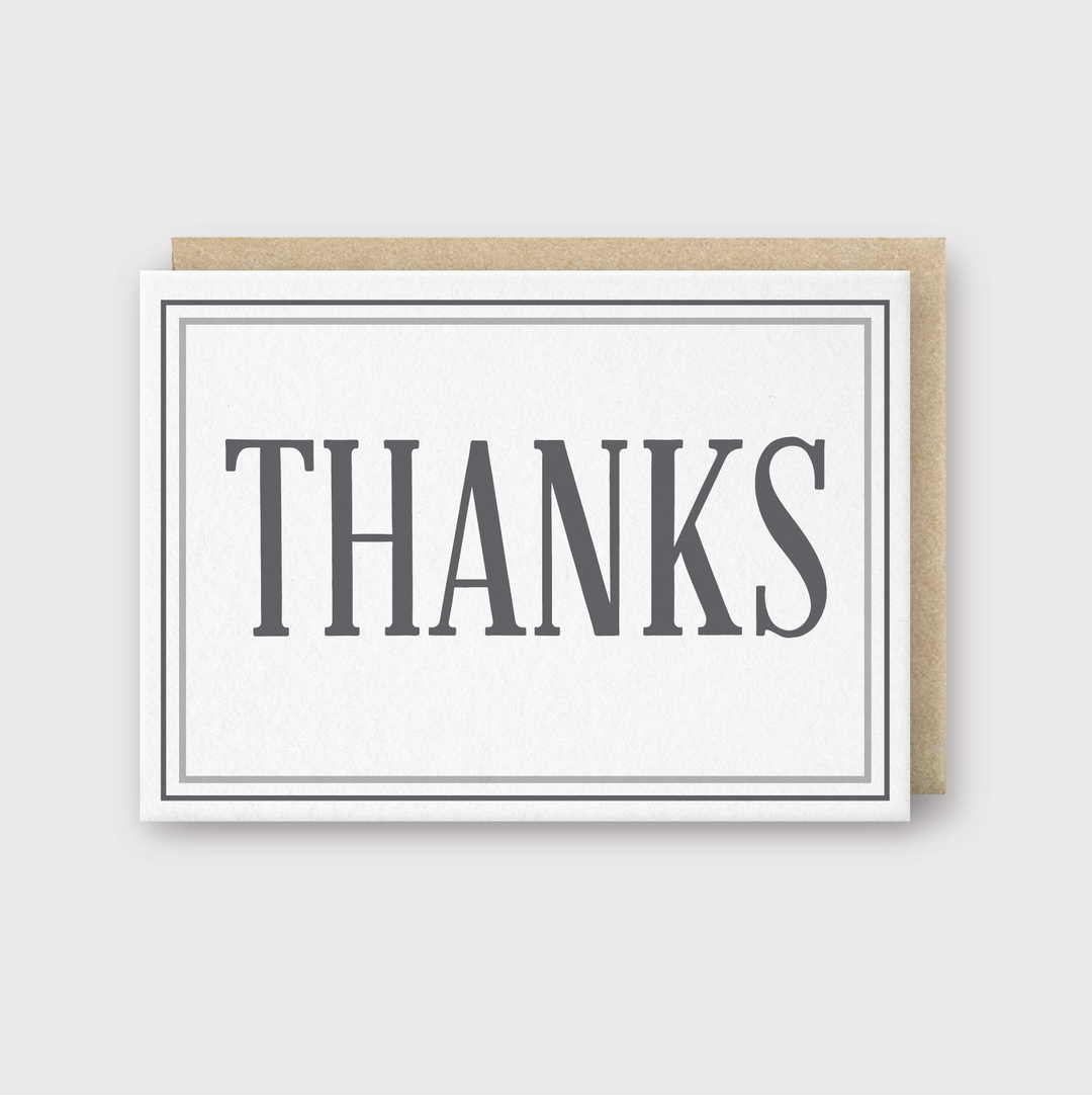 The "Thanks Gray Greeting Card" features a minimalist design with the word "THANKS" prominently printed in gray on its front. This handcrafted letterpress card is made in Seattle and comes with a simple light brown envelope, set against a neutral background.