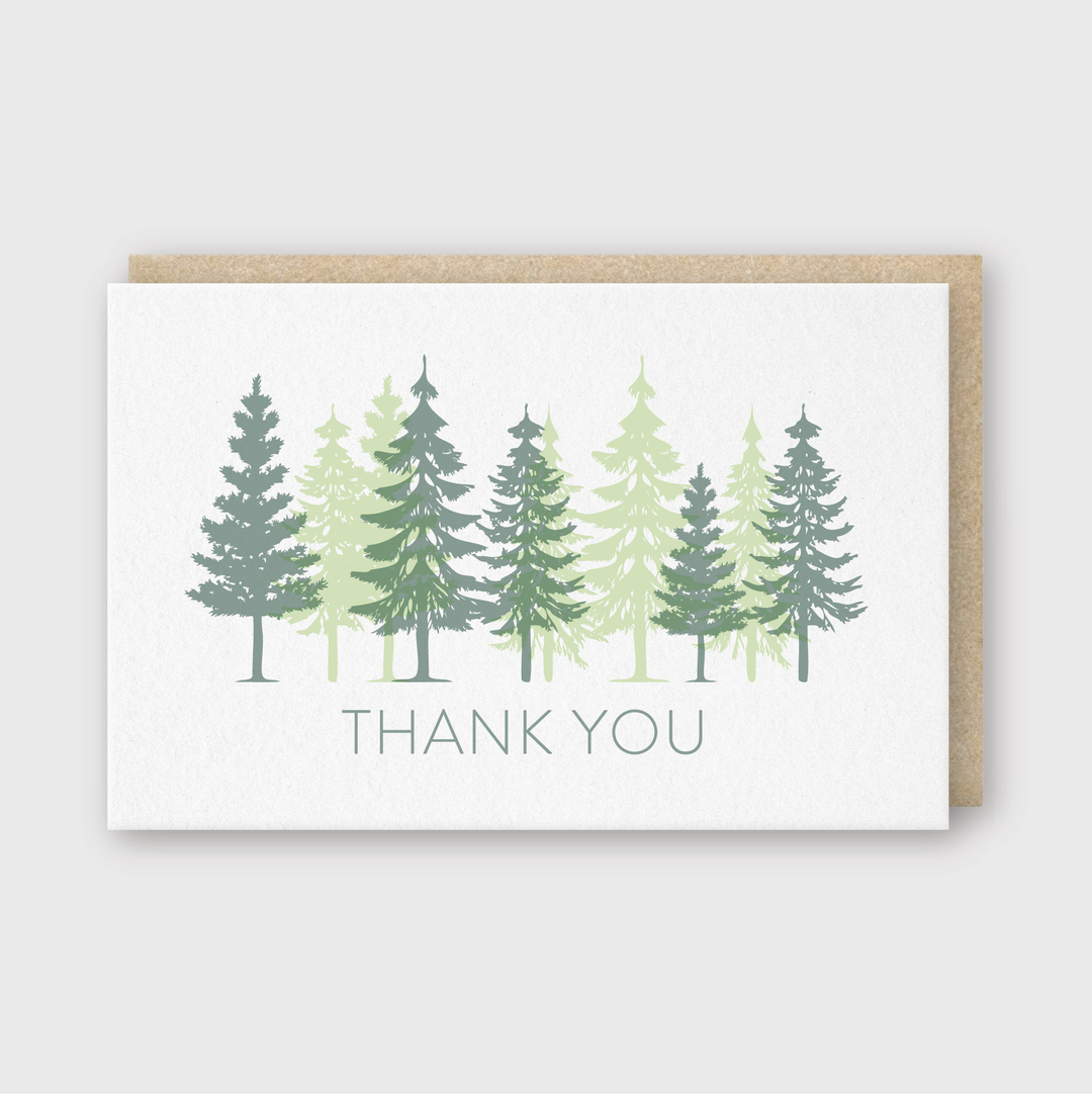 Introducing the "Thank You Trees Overprint Greeting Card"—a beautifully crafted thank you card featuring an illustration of various trees in shades of green. Made using traditional letterpress techniques, the words "Thank You" are elegantly printed below the trees, adding a touch of handcrafted charm. Presented with a brown envelope, it's ready to be delivered.
