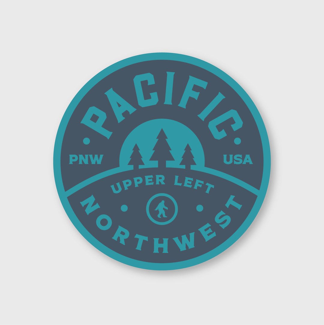 Experience the "PNW Retro Circle Sticker," featuring a circular design perfect for stickers. The words "Pacific Northwest" stand out prominently, surrounded by three trees and a silhouette of Bigfoot at its core. The letters "PNW" and "USA" adorn the sides, while "Upper Left" is situated beneath the trees, all in soothing shades of blue and teal.