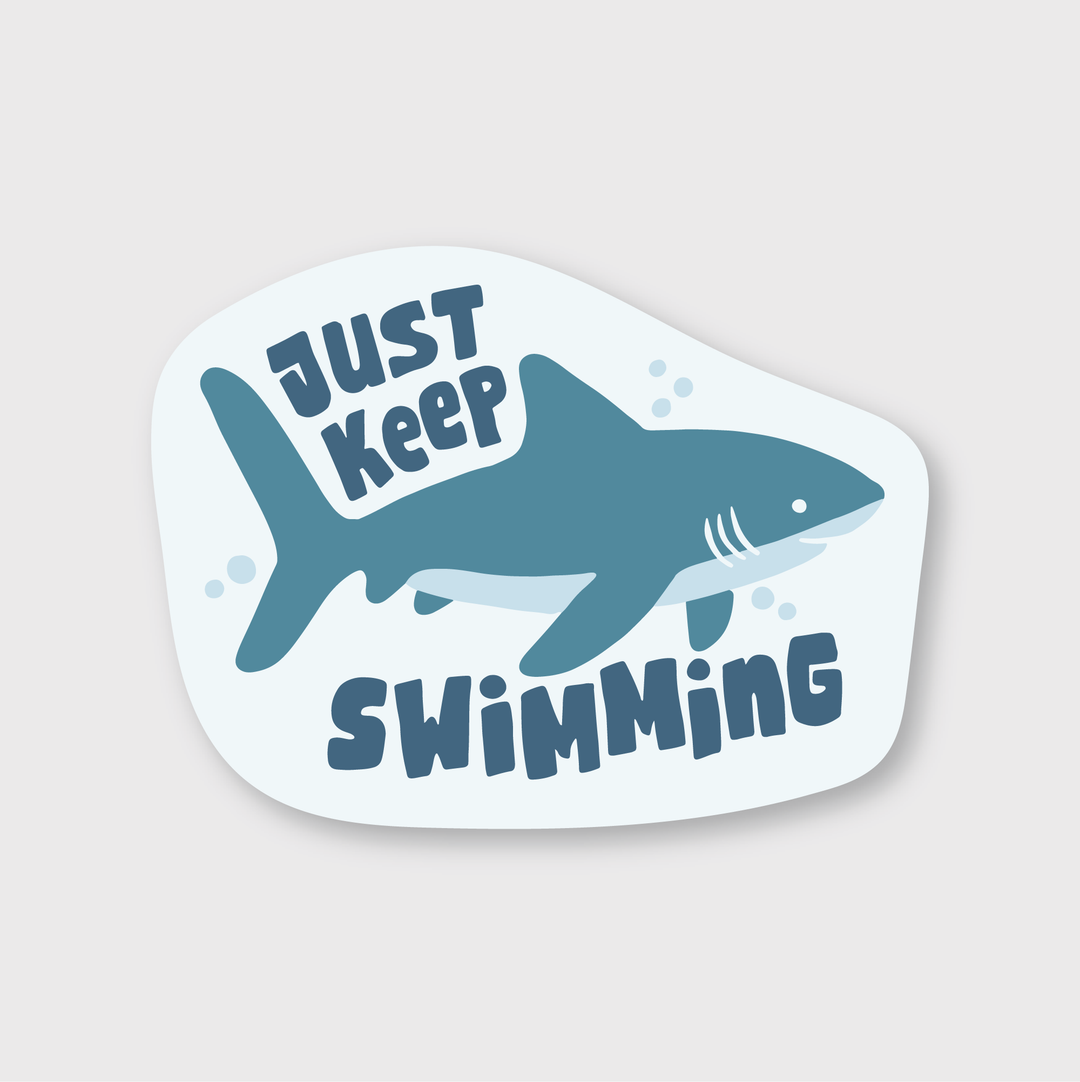 The "Just Keep Swimming" Shark Sticker features a stylized illustration of a shark set against a light background, surrounded by the motivational text "JUST KEEP SWIMMING." This die-cut vinyl sticker comes in shades of blue and is weather-resistant, making it ideal for adding an inspirational touch wherever you choose.