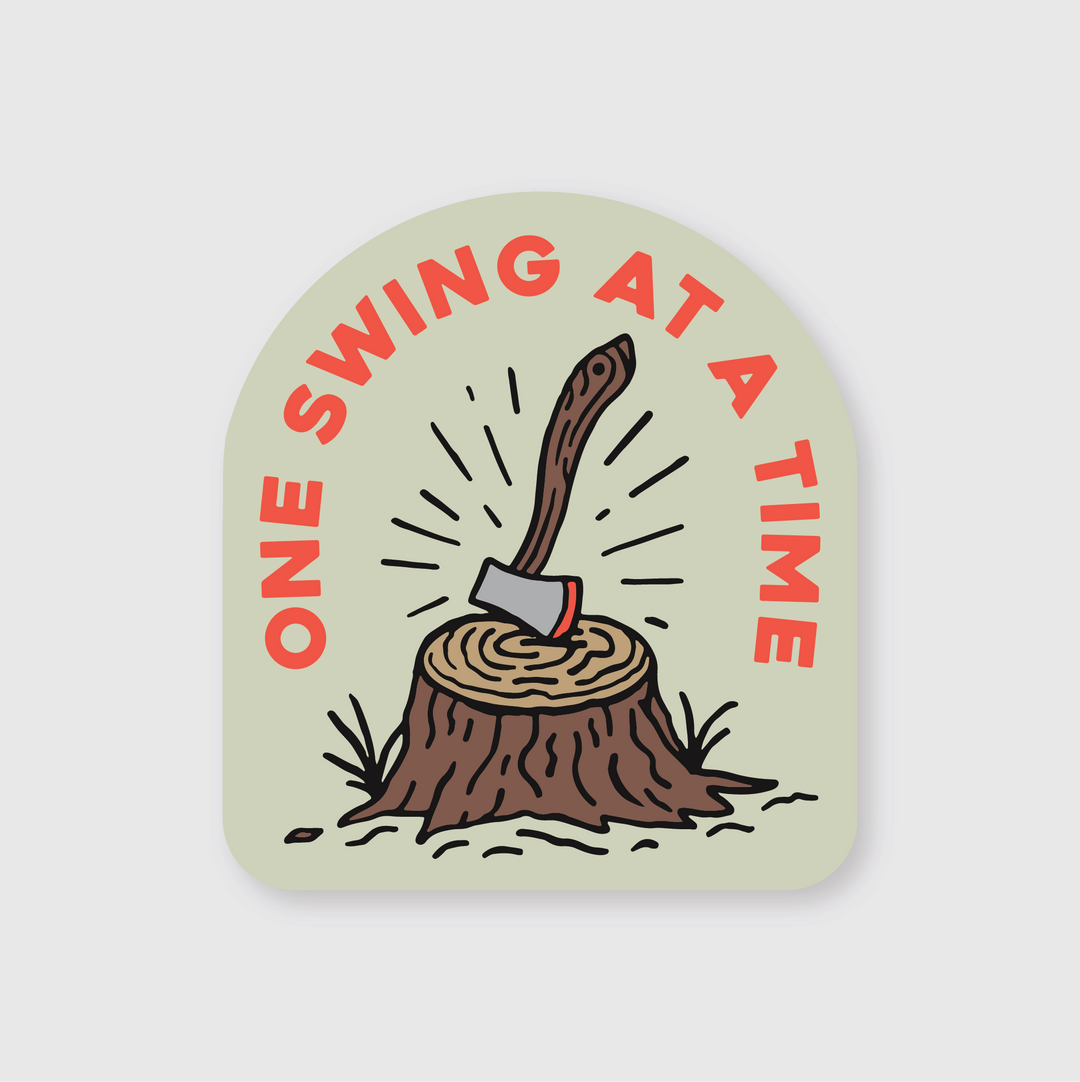 The "One Swing At a Time Sticker" is a die-cut vinyl sticker depicting a tree stump and an ax. It's crafted for durability and weather resistance, ensuring it complements your style in any climate.