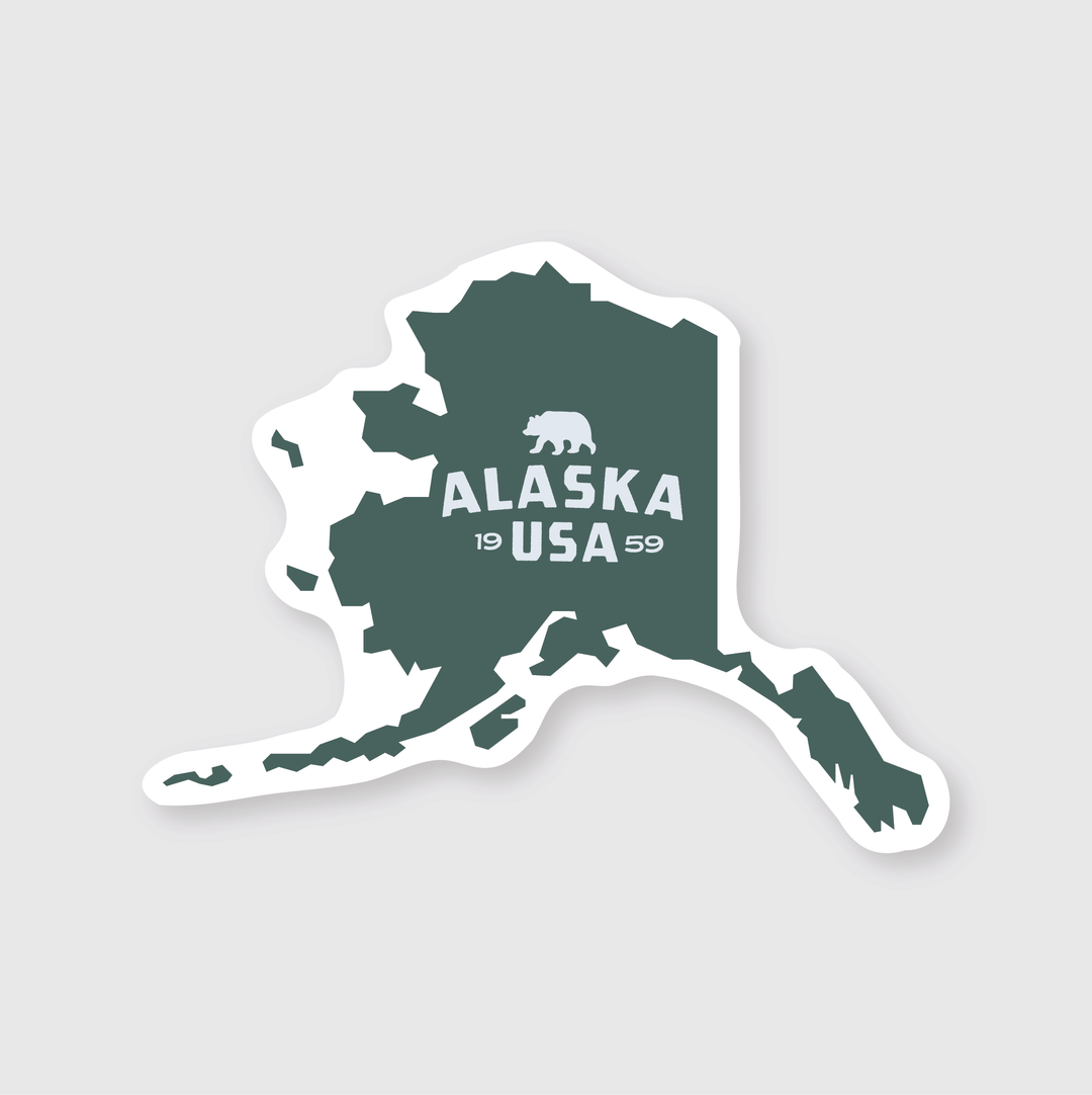 This Alaska Simple State Sticker showcases a simplistic silhouette map of the state with "1959" and "ALASKA USA" in the center. Above the map is an image of a bear. The design is elegantly rendered in dark green on a light gray background, making it a perfect addition to any collection.