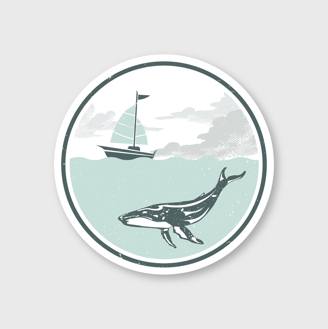 The "Whale Sailboat Sticker" is a round die cut vinyl sticker illustrating a whale swimming underwater with a sailboat on the surface above. It features muted shades of blue and gray, offering a vintage style that enhances any collection.