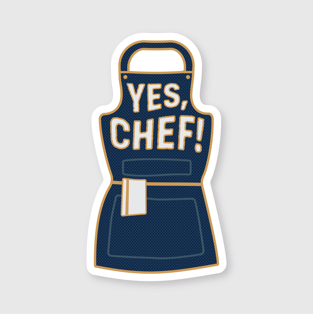 The "Yes Chef! Sticker" features a blue apron with a pocket and the text "YES, CHEF!" along with a small white towel tucked into the pocket. This sticker is die-cut from vinyl, outlined in white against a light gray background. It boasts a high-quality, laminated matte finish that provides water and weather resistance.