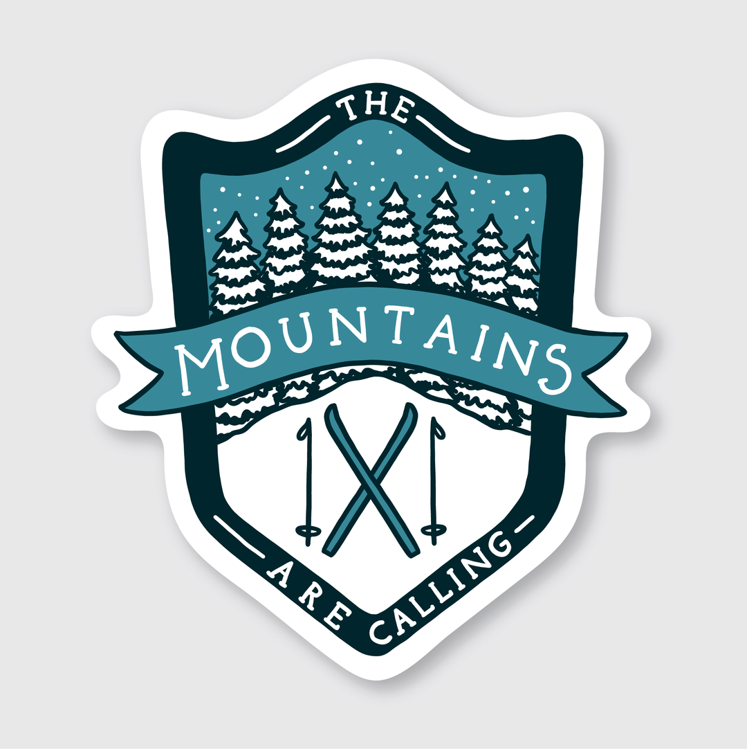 The Mountains Calling Ski Sticker showcases a unique artist-designed badge with snow-covered trees, crossed skis, and poles. The phrase "The Mountains Are Calling" is elegantly displayed in a teal and white winter theme. This durable die-cut vinyl sticker is outdoor rated for longevity.