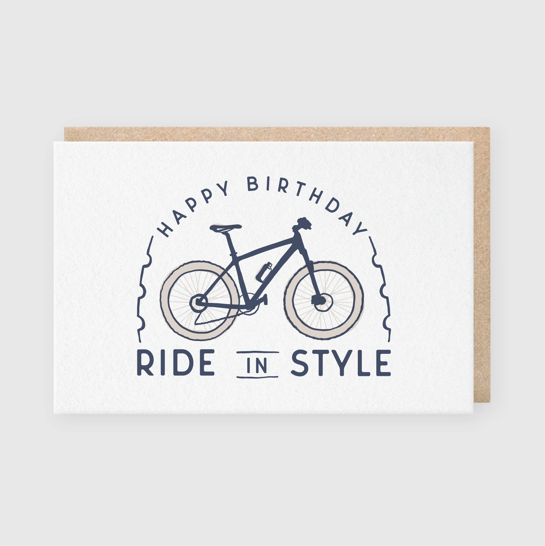 The Ride in Style card features a charming bicycle illustration with the message "Happy Birthday, Ride in Style" in dark blue on a clean white background. It comes with a recycled Kraft envelope, making it an eco-friendly choice for celebrating special birthdays.