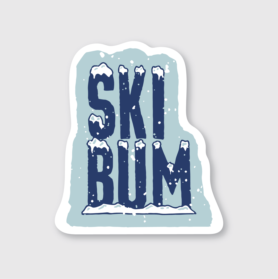 The Snowy Ski Bum Sticker showcases the words "SKI BUM" in bold, dark blue letters covered in snow, set against a light blue background with snowflakes. Crafted by artists, it provides a weather-resistant decorative touch for those who love wintry skiing adventures. Custom Ski Stickers