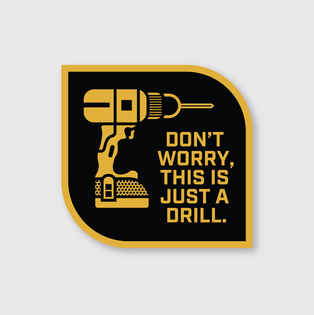 This die-cut vinyl sticker features an illustration of a drill with the text "Don't worry, this is just a drill" on a rounded black and gold background. Handcrafted in Seattle, it adds a touch of personalized gear to any space.