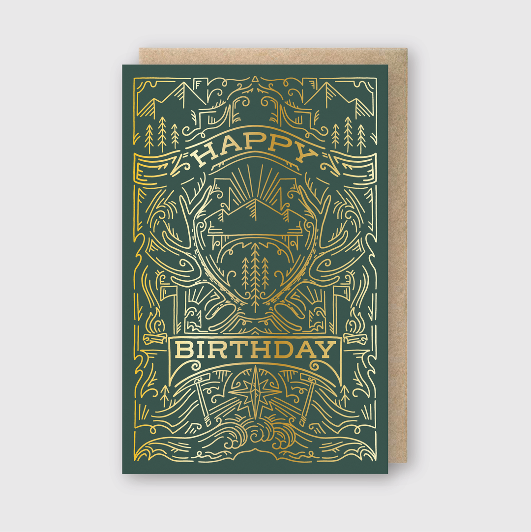 The "Outdoorsman Birthday" card is a great choice for nature lovers, featuring a detailed gold and green design. The "Happy Birthday" message is surrounded by beautiful patterns of mountains, trees, and antlers. This letterpress greeting card comes with a brown envelope, making it perfect for outdoor enthusiasts.
