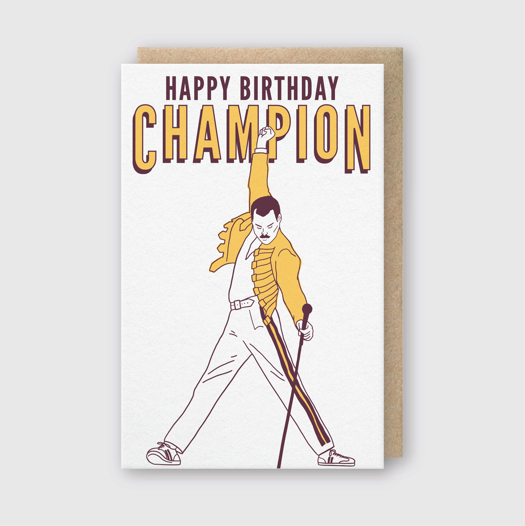 The Happy Birthday Champion Greeting Card showcases a lively image of someone in a yellow jacket energetically posing with a microphone stand. It features bold letterpress text saying "Happy Birthday Champion" and is complemented by a traditional brown envelope.