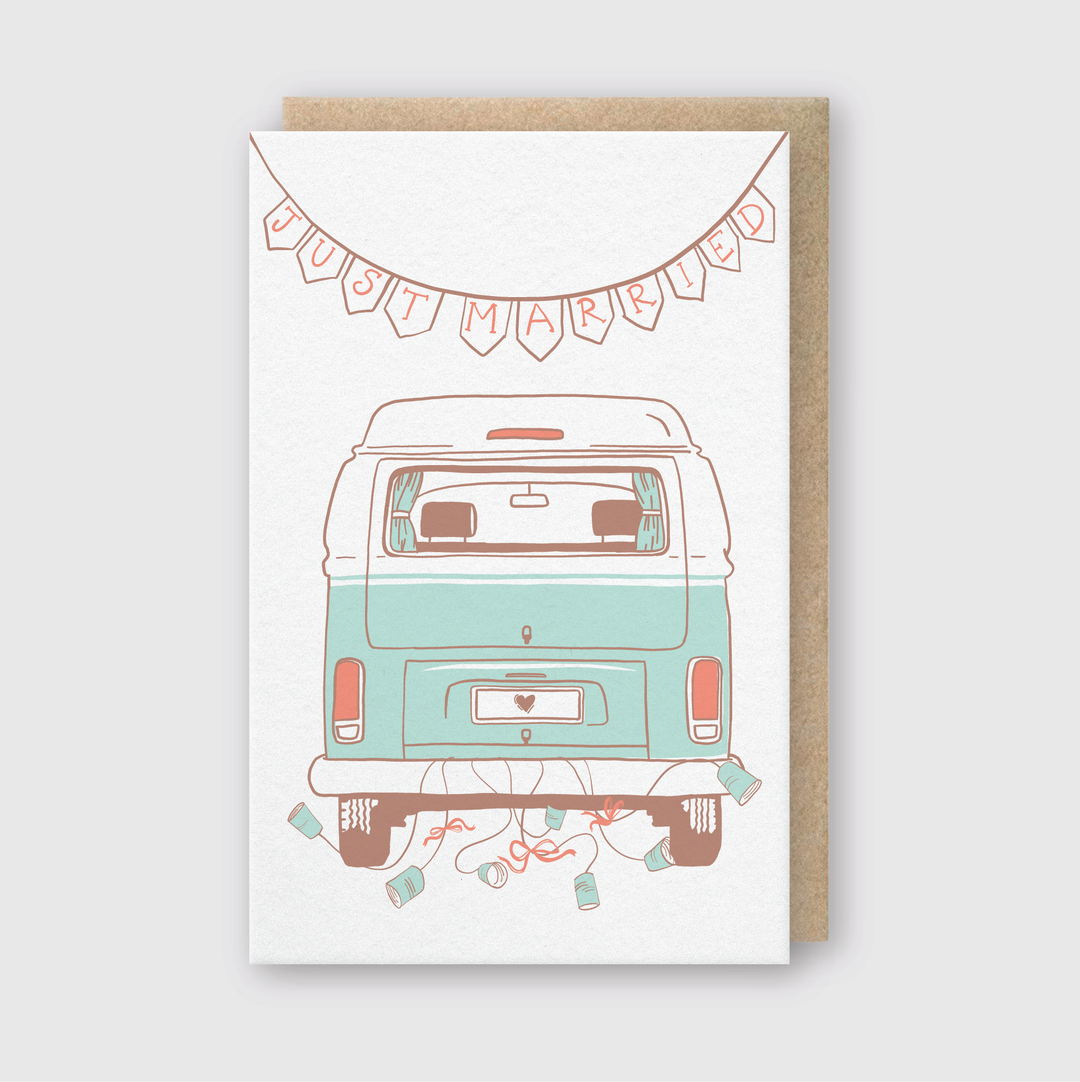 The Just Married Camper Van Wedding Card features a charming illustration of a blue and white camper van adorned with bunting, perfect for couples who love travel and adventure. The dangling tin cans add to the festive atmosphere. It comes with a rustic brown envelope that embodies the joy of the occasion.