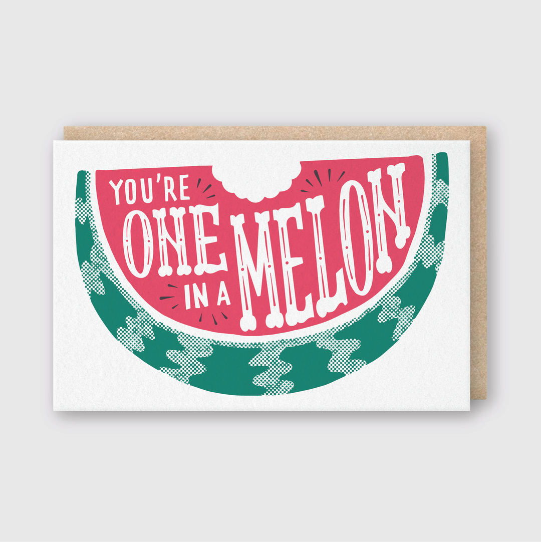 The "One in a Melon" greeting card by Pike Street Press showcases a delightful watermelon slice design, with the phrase "You're one in a melon" creatively placed on the red part of the fruit. Crafted from recycled paper, this card beautifully contrasts with its light background.