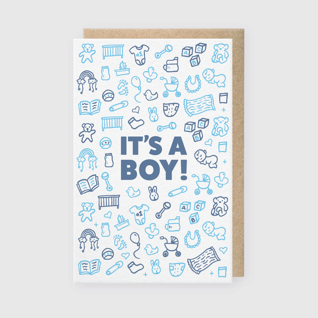 The "It's A Boy Greeting Card" is a charming letterpress creation featuring delightful blue and white baby-themed doodles. These include pacifiers, bottles, and teddy bears surrounding the exuberant message "IT'S A BOY!" in bold blue letters.