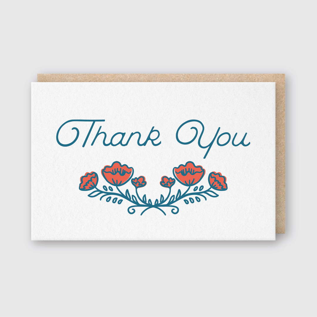 The Thank You Poppies Greeting Card features a stylish "Thank You" in elegant blue script. Below, vivid red and blue floral designs capture the beauty of poppies. It includes a brown envelope and is displayed against a light gray background, emphasizing exquisite letterpress craftsmanship.