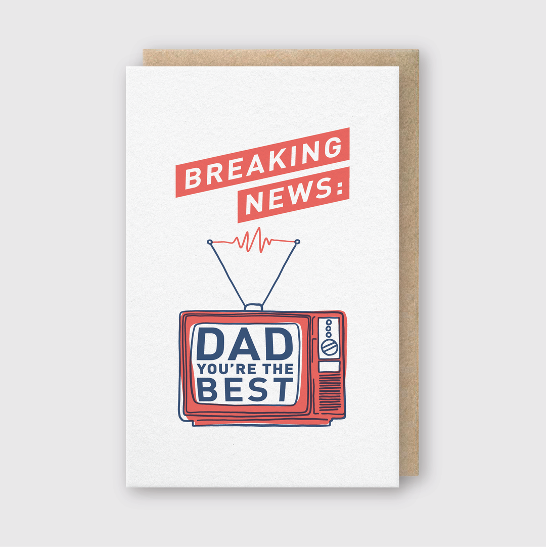 The "Breaking News Dad Greeting Card" is a handcrafted card featuring a retro TV illustration. The screen displays the blue text "Dad You're the Best," while red text on a banner above the TV announces "Breaking News:". A brown envelope in the background makes it an ideal gift for the #1 Dad.