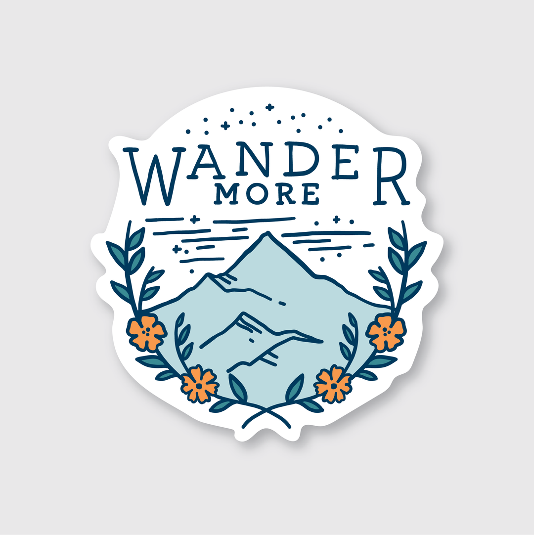 This die cut vinyl sticker, titled "Wander More," showcases a mountain scene with stars and is surrounded by orange flowers and green leaves. Expertly crafted to be weather-resistant, its unique design is an inspiration for adventure.