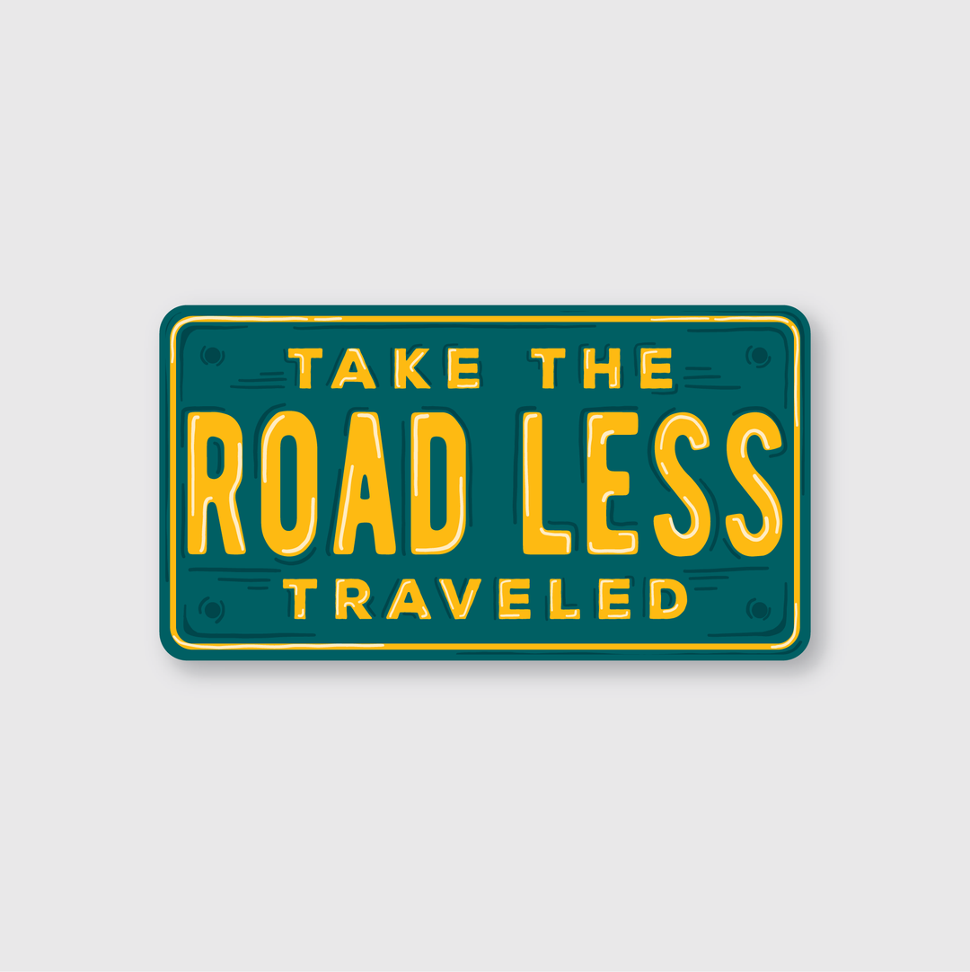 The Road Less Traveled License Sticker by Pike Street Press showcases a vintage-style design with a green background and yellow text that reads, "Take the Road Less Traveled." This product captures the essence of quality craftsmanship typical of Seattle's artisan markets.