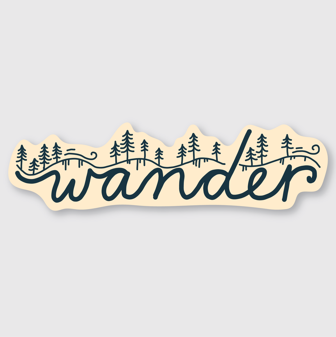 The Wander Hillside Sticker is a die-cut vinyl sticker with the word "wander" in cursive. The design features letters adorned with pine trees and a forest landscape motif in dark green on a pale background.