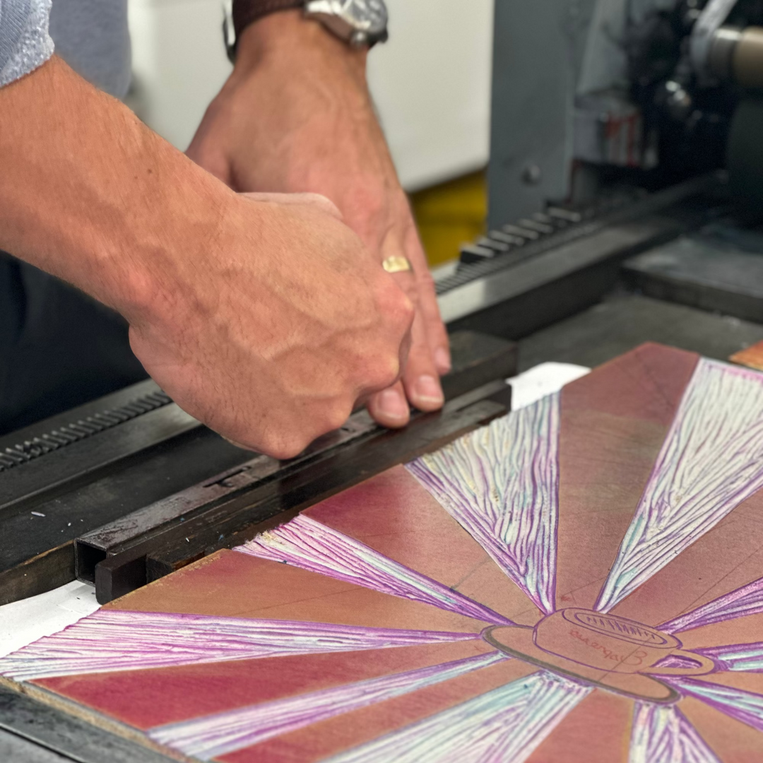 Person working with a colorful stained glass panel on a machine.