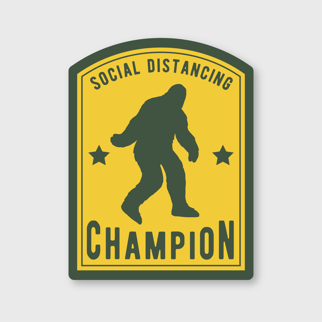 The Social Distancing Champion Sticker features a playful vinyl design with Bigfoot's silhouette at the center. It is labeled "Social Distancing Champion" and includes a yellow background, green borders, and two stars, making it perfect for those who appreciate whimsy and style.