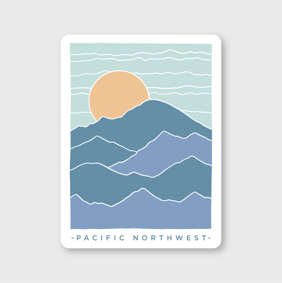 The PNW Scenery Sticker features a minimalist illustration of layered mountains in various blue shades, highlighted by a prominent orange sun. It's set against a light blue sky with wavy lines. The words "PACIFIC NORTHWEST" appear at the bottom, making it ideal for those who wish to celebrate the natural beauty of Seattle.