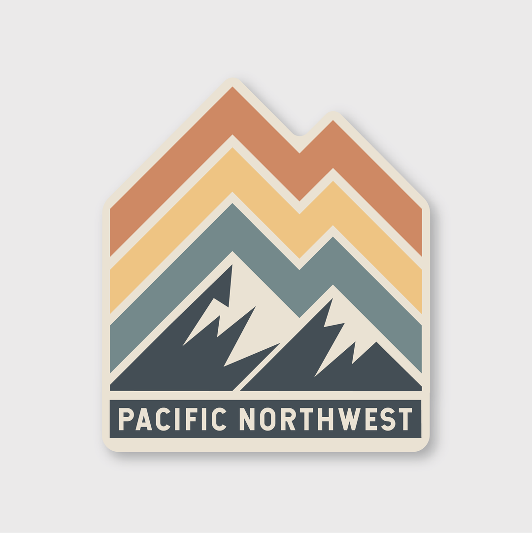 Sticker design features geometric mountain layers in vibrant shades of orange, yellow, teal, and dark blue. The phrase "PACIFIC NORTHWEST" is prominently displayed at the base, capturing an aesthetic inspired by Seattle. This is known as the PNW Mountains Rising Sticker.