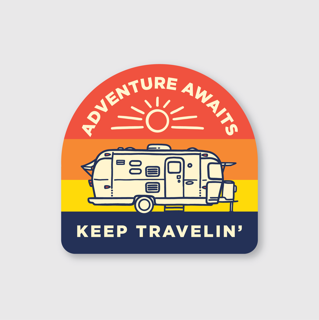 The Keep Travelin' Sticker features a retro-style illustration on weather-resistant vinyl. It showcases a sunset gradient background, with a die-cut design that includes a camper van. The phrases "Adventure Awaits" and "Keep Travelin’" are prominently displayed above and below the van, along with a sun above it, making it perfect for your adventures.