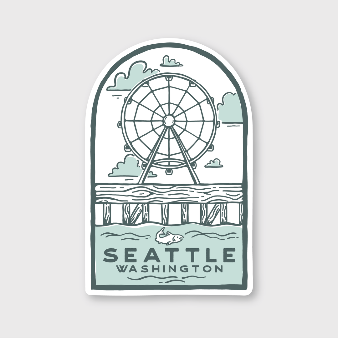 This weather-resistant, die-cut vinyl sticker features an illustration of a Ferris wheel by the pier over water with a fish, set against a cloudy sky. "Seattle Washington" is elegantly printed at the bottom.